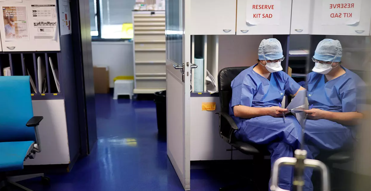 A medical staff member, wearing a face mask, takes a break in an intensive care unit for coronavirus disease
