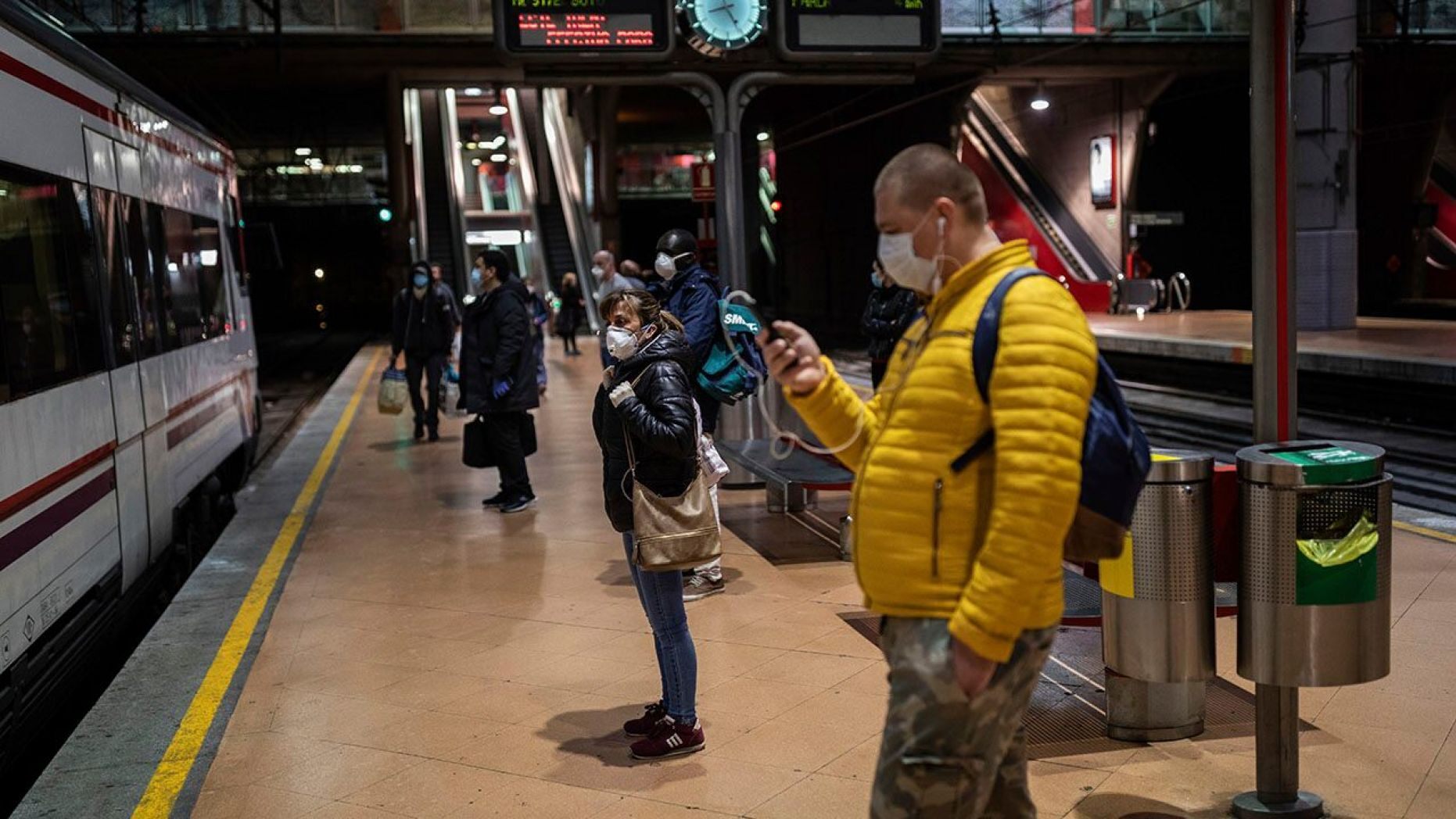 Commuters wearing face masks to protect against coronavirus wait at the platform of Atocha train station in Madrid on Monday. 