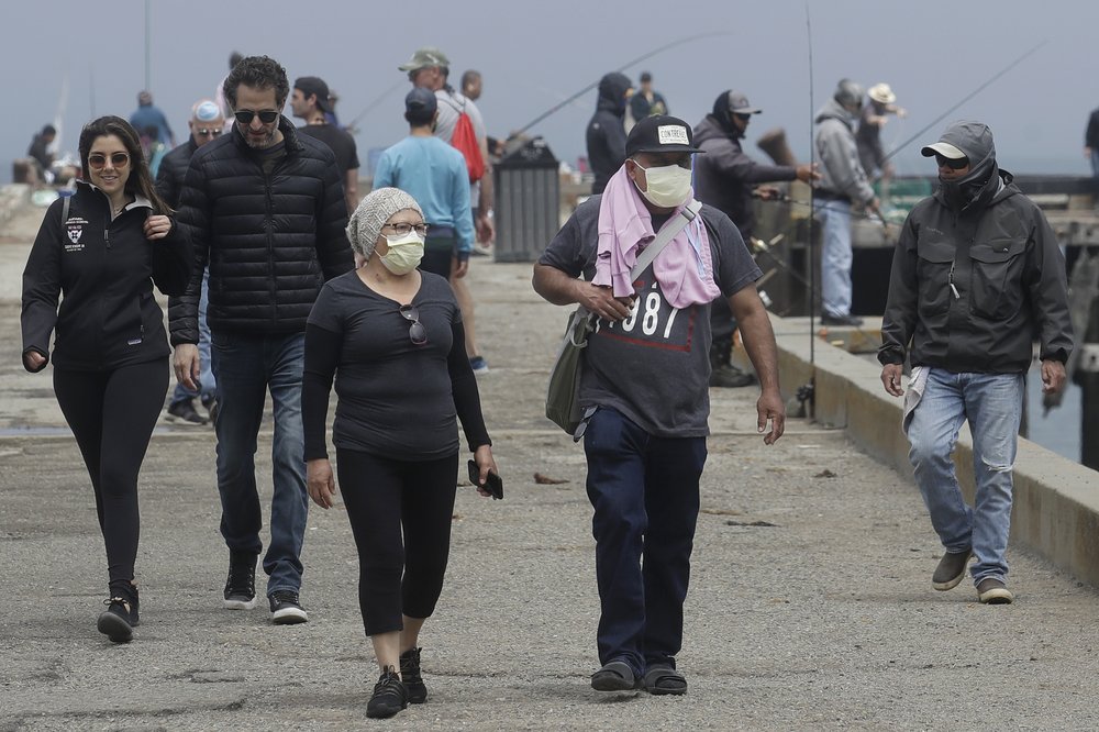 Some people wear face masks while walking on a pier during the coronavirus outbreak in San Francisco, Saturday, May 16, 2020. 