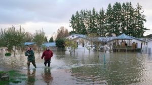Sisters Myranda, (L), and Krysten Archer walk through floodwater from their uncle's home in Sedro-Woolley, Wash., on Nov. 15, 2021. (Elaine Thompson/AP Photo)